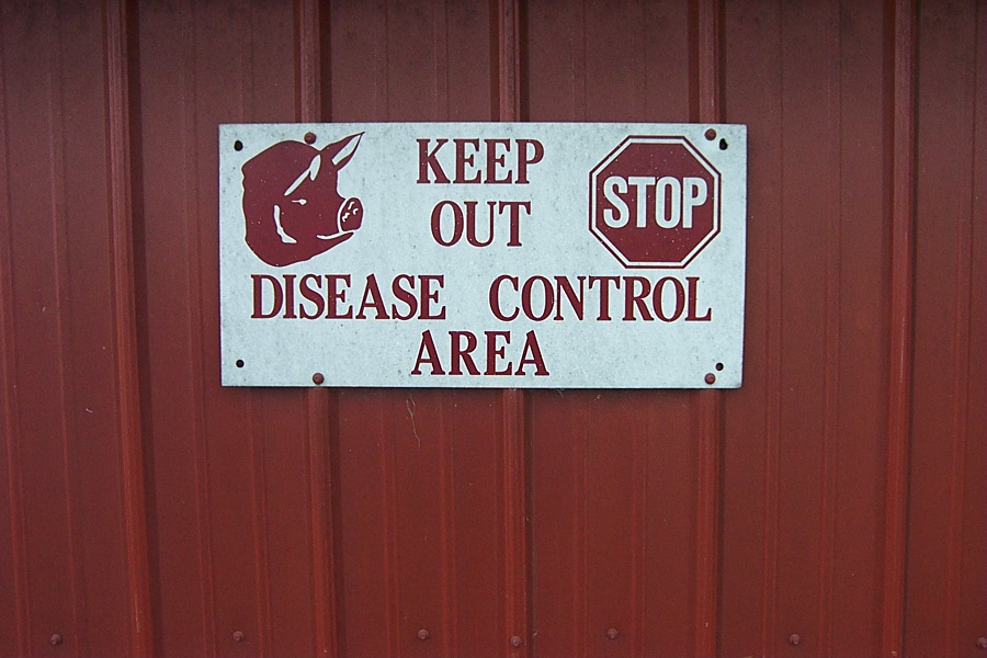 A sign on a barn door reading &#039;Keep Out - Disease Control Area&#039;