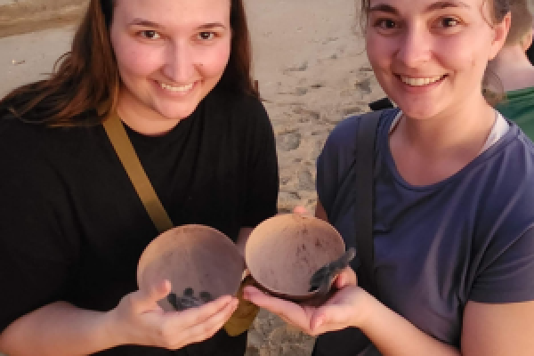 DVM students Tess Schaefer (left) and Madison Baumgartner hold newly hatched baby sea turtles.