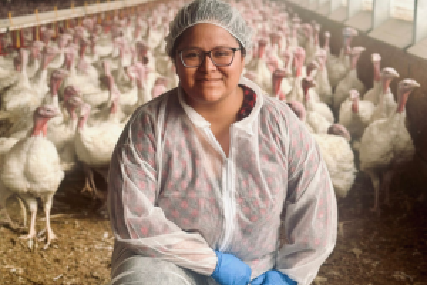 Gabby Kiesel kneels in a poultry barn