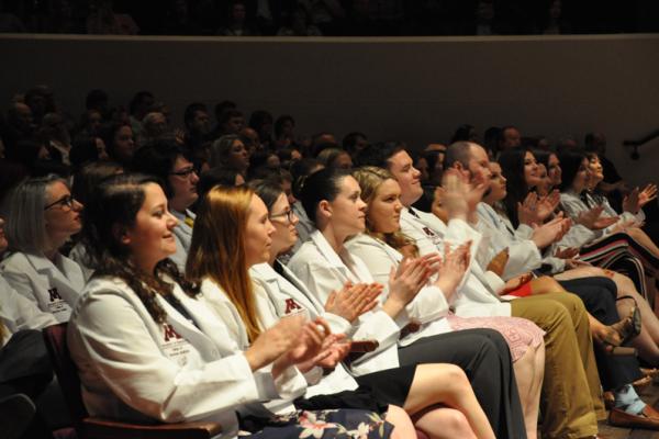 Veterinarian students seated and applauding at a white coat event